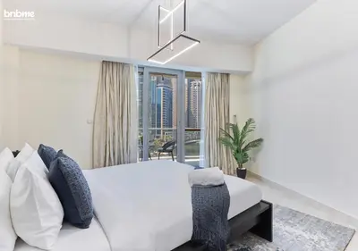 a bedroom with a white bed and a large window at bnbmehomes - DAMAC Waves Tower in Dubai