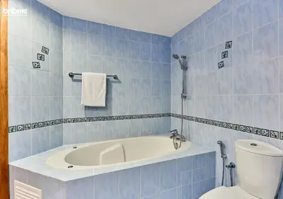 a blue tiled bathroom with a tub and a toilet at bnbmehomes - DAMAC Waves Tower in Dubai