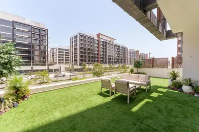 an apartment patio with grass and chairs and buildings at Chic 1BR Apartment in Azizi Riviera, Meydan in Dubai