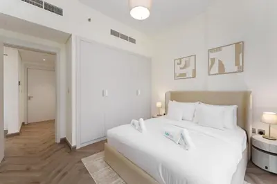 a white bedroom with a large bed with white pillows at Chic 1BR Apartment in Azizi Riviera, Meydan in Dubai