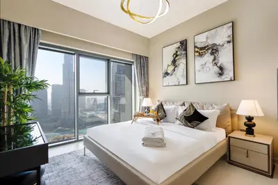 a bedroom with a large bed with a large window at Livbnb - 3BR Deluxe suite w/ Burj Khalifa & Fountain Views in Dubai