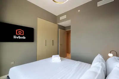 a bedroom with a bed and a tv on the wall at Livbnb - 3BR Deluxe suite w/ Burj Khalifa & Fountain Views in Dubai