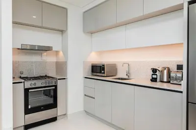 a kitchen with white cabinets and stainless steel appliances at Chic Apartments in Marina Vista Emaar Beachfront in Dubai
