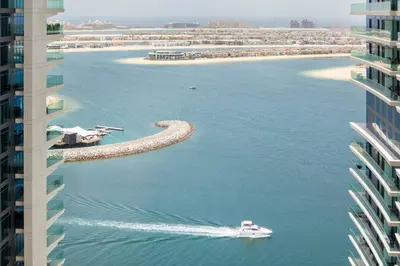 a boat in the water next to some buildings at Chic Apartments in Marina Vista Emaar Beachfront in Dubai