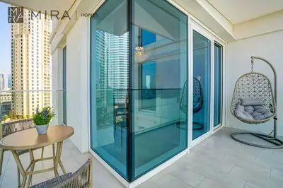 a glass balcony with a table and a chair at Mira Holiday Homes - Luxury 2 bed apartment in La Vie in Dubai