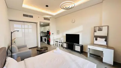 a bedroom with a bed and a living room with a television at Oval Tower Furnished Studio Business Bay in Dubai