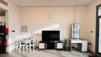 a living room with a tv and a table with chairs at Oval Tower Furnished Studio Business Bay in Dubai