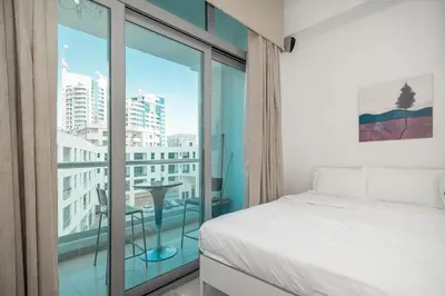 a bedroom with a bed and a balcony with a table at StoneTree - Chic Studio - Near Beach in Dubai