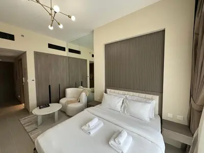 a bedroom with a large white bed and a chair at ASHRI HH, STANDARD STUDIO IN STUDIO CITY in Dubai