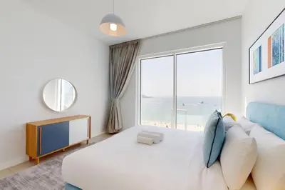 a bedroom with a large white bed and a large window at La Vie JBR - Breathtaking Two Bedroom in Dubai
