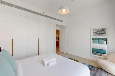 a white bedroom with a bed and a couch at La Vie JBR - Breathtaking Two Bedroom in Dubai