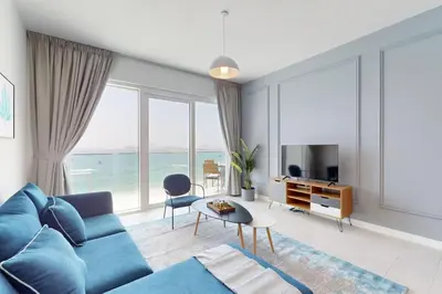 a living room with a blue couch and a view of the ocean at La Vie JBR - Breathtaking Two Bedroom in Dubai