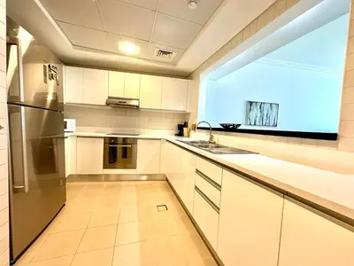 a kitchen with white cabinets and a large window at 1BR Apartment, Full Sea and JBR View in Dubai