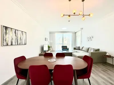 a living room with a wooden table and red chairs at 1BR Apartment, Full Sea and JBR View in Dubai