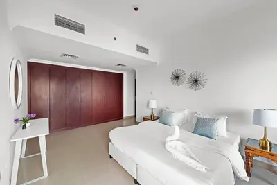 a white bedroom with a large bed and a table at Dubai Marina 3BR Apartment, Steps to Marina Walk, Marina Beach & JBR in Dubai