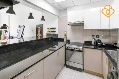a kitchen with white cabinets and black counter tops at Keysplease 1 BR Polo Residence, Meydan in Dubai