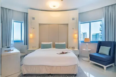 a bedroom with a large bed and a blue chair at FIRST CLASS 2BR Modern Downtown Retreat in Dubai