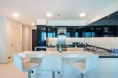 a kitchen with a large white island with two chairs at FIRST CLASS 2BR Modern Downtown Retreat in Dubai