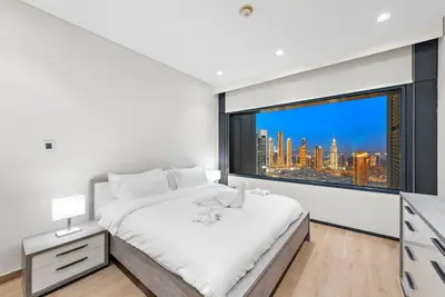 a white bedroom with a large window with a city skyline at FIRST CLASS 1BR Stunning Burj Khalifa Views in Dubai