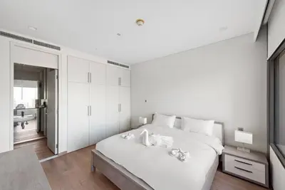a white bedroom with a large bed and a bathroom at FIRST CLASS 1BR Stunning Burj Khalifa Views in Dubai