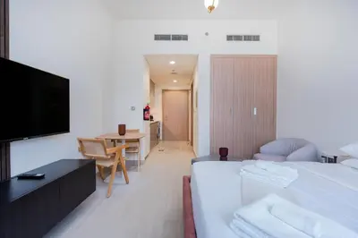 a bedroom with a bed and a television and a table at 12 min from downtown - Studio - Azizi Riviera in Dubai