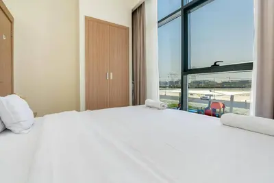 a bedroom with a white bed and a large window at 1 bedroom - 12 min from downtown - Azizi Riviera in Dubai