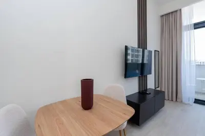 a living room with a wooden table and a television at Studio - 12 min downtown - Pool - Azizi Riviera in Dubai