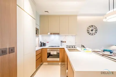 a kitchen with white counters and wooden cabinets at Elegant 2BR Apartment at The Address Residences Dubai Opera, Downtown Dubai by Deluxe Holiday Homes in Dubai