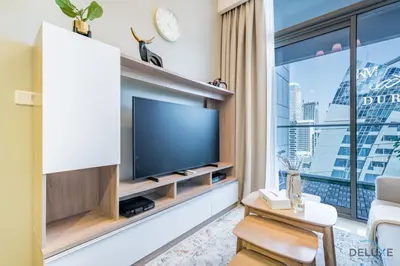 a living room with a tv and a large window at Calm 1BR in Vera Tower, Business Bay by Deluxe Holiday Homes in Dubai