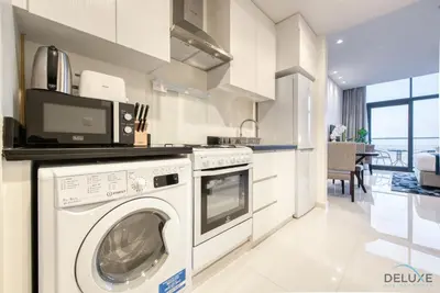 a kitchen with a washing machine and a microwave at Charming Studio in Celestia A, Dubai South by Deluxe Holiday Homes in Dubai