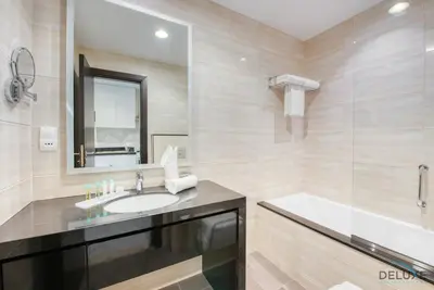 a bathroom with a sink and a tub and a mirror at Charming Studio in Celestia A, Dubai South by Deluxe Holiday Homes in Dubai