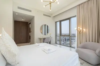 a white bedroom with a large bed and a chair at New Listing & Vida Creek Beach & Beach Access in Dubai