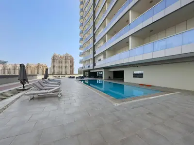 a building with a swimming pool and lounge chairs at Modern 1 bedroom apartment in Sports City in Dubai