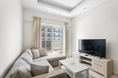 a living room with a couch and a flat screen tv at Modern 1 bedroom apartment in Sports City in Dubai