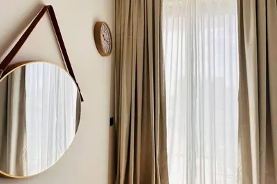 a mirror hanging on a wall next to a window at Modern One Bedroom JVC in Dubai