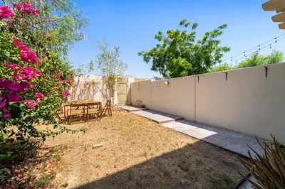 a backyard with a fence and a table and flowers at Stonetree - The Springs 5 - Peaceful Community in Dubai