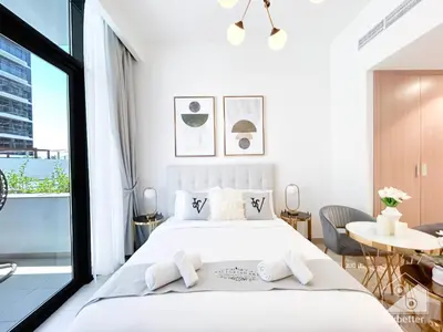 a white bedroom with a large bed and a table at Elegance at Aziz Riviera Studio & Balcony in Dubai