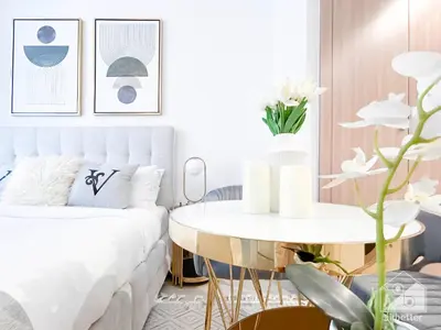 a bedroom with a white bed and a white table at Elegance at Aziz Riviera Studio & Balcony in Dubai