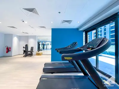 a gym with a treadmill and a blue wall at Elegance at Aziz Riviera Studio & Balcony in Dubai