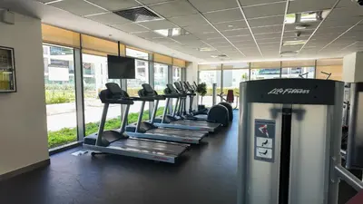 a row of treadmills in a gym with windows at Luxurious New Brand 2Br at Mulberry 2 at Park Heights Building A2 - Dubai Hills in Dubai
