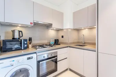 a kitchen with white cabinets and a washer and dryer at STAY BY LATINEM Luxury 1BR Holiday Home CVR A609 near Burj Khalifa in Dubai