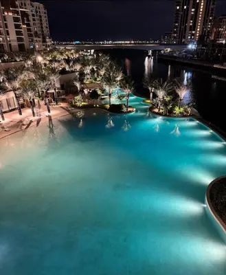 a large pool of blue water at night at Burj Khalifa view & Creek sea view in Dubai
