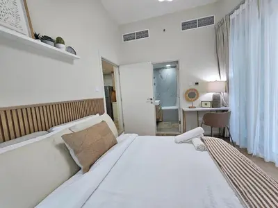a white bedroom with a bed and a desk at Golden Hour Marina View in Dubai