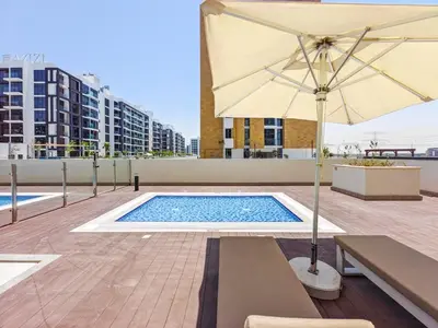 a swimming pool with an umbrella and a table and benches at Zen Condo With Burj Khalifa View In Vibrant City in Dubai