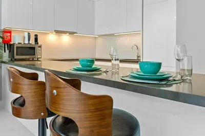 a kitchen with two chairs and a counter with plates and glasses at Premium 1-BR with Exquisite Layout in District One in Dubai