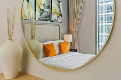a mirror in a bedroom with a bed with orange pillows at Premium 1-BR with Exquisite Layout in District One in Dubai