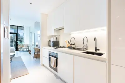 a white kitchen with a sink and a counter at Cozy Central Home with Full Burj View in Dubai