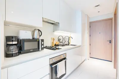 a white kitchen with a microwave and a stove at Cozy Central Home with Full Burj View in Dubai