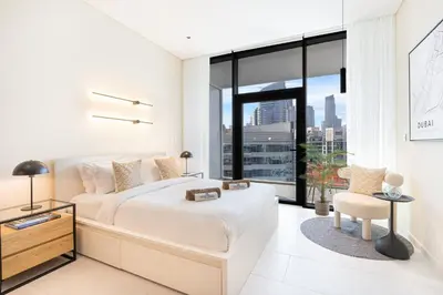 a white bedroom with a large bed and a large window at Cozy Central Home with Full Burj View in Dubai