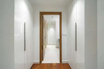 a hallway with white walls and a wooden door at Experience City Walk - Spacious Haven - 2 Bedroom plus Maid's Room in Dubai